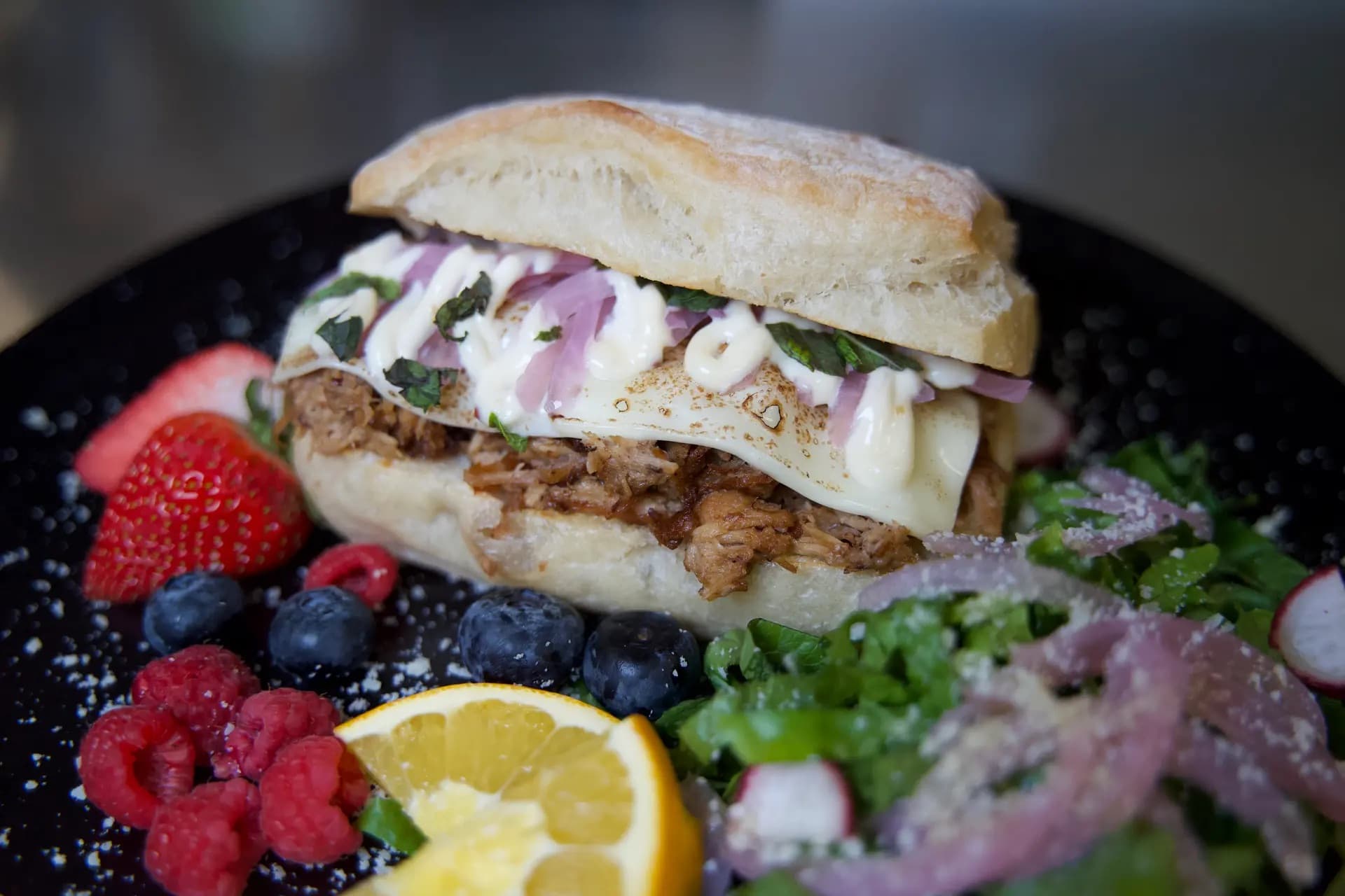 The Monroe - Succulent, slow-cooked pulled pork topped with melted cheese and vine-ripened tomatoes, served alongside a crisp side salad and fresh seasonal fruit.